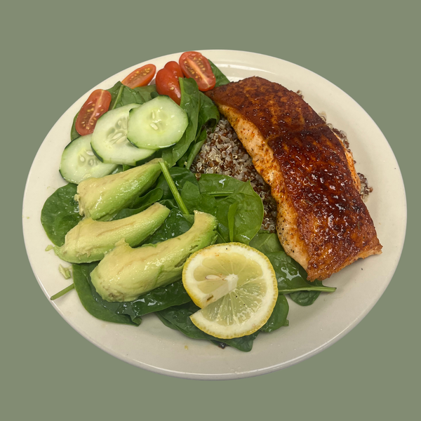 Plated dish with salmon, salad, and lemon over a bed of quinoa.