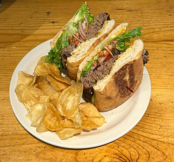 Our delicious Grass fed beef patty topped with purple onion slices, red tomatoes, green leaf lettuce served on lightly toasted ciabatta bun, served with crunchy golden house-made potato chips.