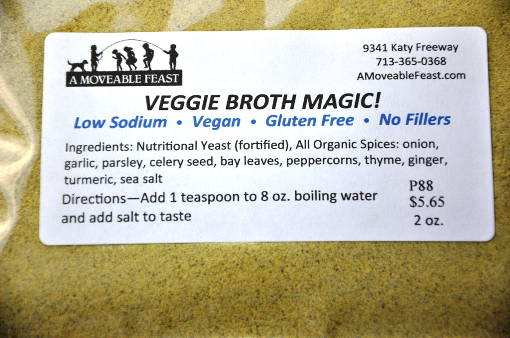 A resealable plastic pouch containing 2 ounces of A Moveable Feast's golden colored Veggie Broth Magic. The pouch label describes the ingredients, which include all organic spices, and fortified nutritional yeast.